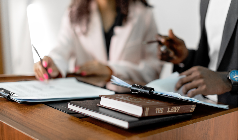 Deux juristes ou avocats examinant des documents juridiques relatifs à la protection des données à caractère personnel, avec un livre intitulé “The Law” en premier plan.