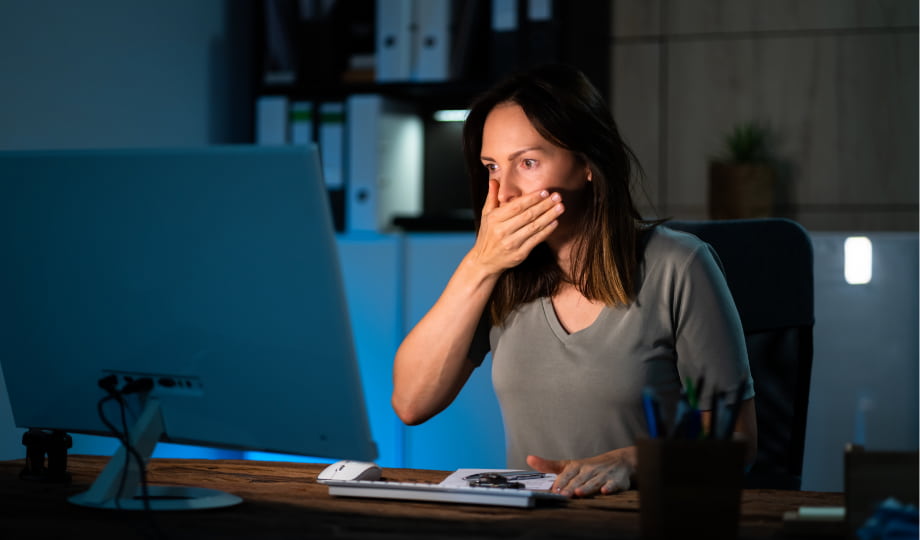 Femme choquée devant son écran, illustrant les risques et incidents opérationnels que Dora vise à prévenir dans les systèmes utilisant l’IA.